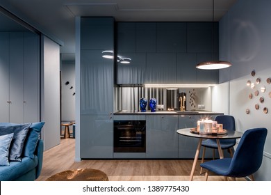 Dark home interior in blue with open kitchen and dining area with round table