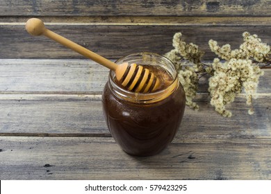 Dark Honey In The Jar With Flowers On The Wooden Background