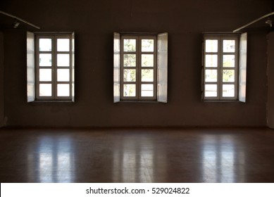 Dark interior with light coming in through three opened windows.