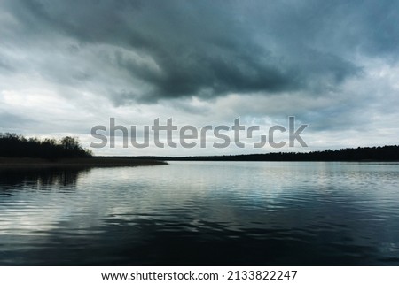 Dark lake landscape. Stormy weather scenic view. Melancholic landscape. Rainy day by the lake. Sad panoramic background.