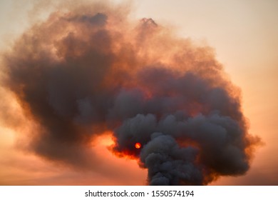 Dark and large bush fire cloud covers sky as sunset concludes. Orange sun shines through the intoxicating cloud. - Powered by Shutterstock