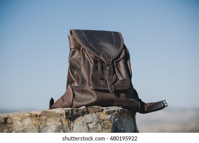 Dark leather backpack in a stone wall at the countryside.