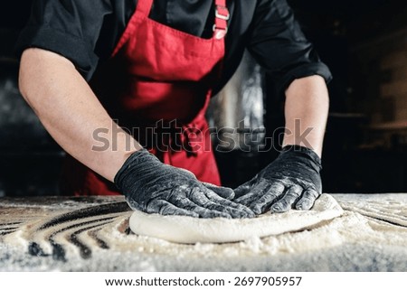 Dark light Chef preparing pizza dough in pizzeria kitchen.