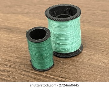 Dark and light green thread spools on dark brown oak surface