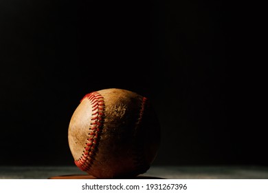 Dark Lighting Over Old Dirty Baseball With Black Background For Sports Nostalgia.