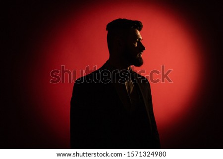 Dark male silhouette. Silhouette of man with beard over red background with copy space