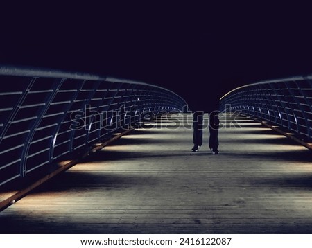 Dark man walk on the bridge at night. Like a dark shadow. Dark background. Mysterious photo.