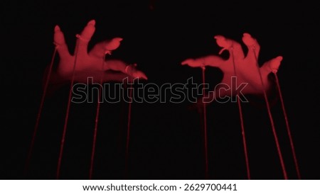 Dark Manipulation: Hands Controlling Red-String Puppets