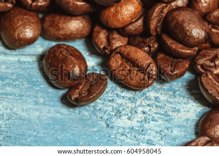 Dark many roasted coffee beans on blue background.