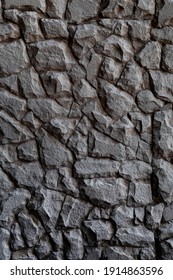 Dark masonry wall texture. Black stones and rocks of different shape, gray background, vertical photo. Texture for interior and exterior design