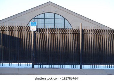 A Dark Metal Fence And A Ride Share And Curbside Delivery Sign                              