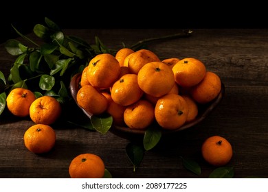 dark mode concept photo, oranges arranged on a clay plate (natural concept) with lighting from the left side )