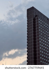 Dark modern skyscraper against a dramatic cloudy sky