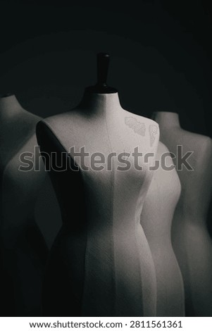 Dark moody studio shot of three vintage tailor mannequins standing in shadows