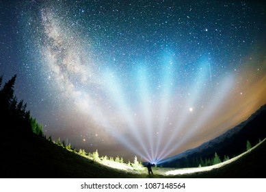 The dark mountain night shines with millions of stars over the fabulous Alpine peak in the Carpathians, the Milky Way of the Galaxy passes over a coniferous forest with a huge arc