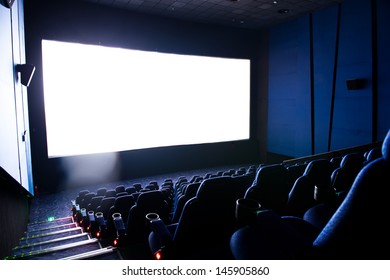 Dark movie theatre interior. screen and chairs.