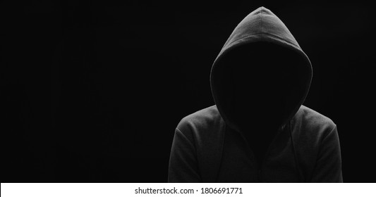dark mysterious man in a hoodie is hiding his face, hacker, anonymous. 