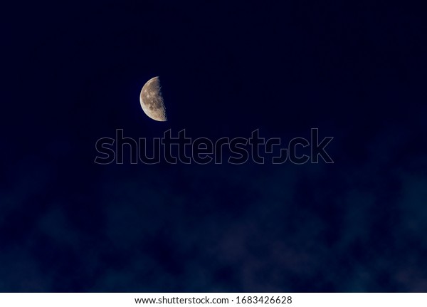 Dark night with half moon on sky, detail texture on\
moon surface. Mist appear under moon light, mist position is below\
image. Emotion of lonely, scary, silent. Blank pace for text. Dark\
side of moon.