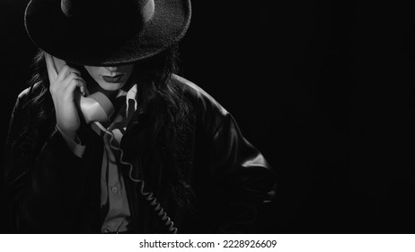 Retrato oscuro de una detective sosteniendo un receptor de teléfono retro. detective privado, espía, concepto de investigación. instantánea en blanco y negro