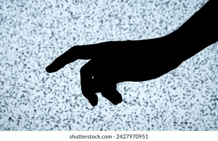 Dark outline of a persons outstretched hand and pointing finger high contrast with the bright, textured backdrop of a TV screen display with white noise. Horror, creepy scary hand shape concept - Powered by Shutterstock