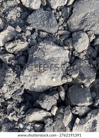 Dark overburden material with rough texture commonly found in mining and industrial excavation areas.