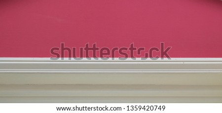 Dark pink wall with cream wood door surround below - with copy space - image