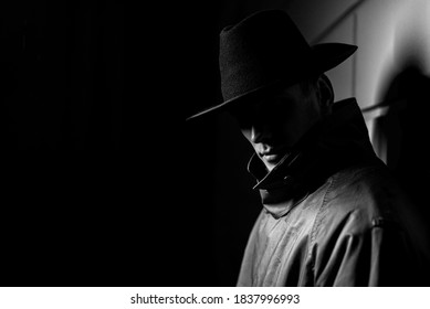 Dark Portrait Of A Man In A Raincoat With A Hat At Night On The Street In A Crime Noir Style