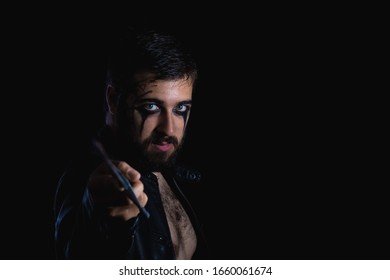 Dark Portrait Of Modern Shaman Young Man With Viking Painting. Handsome Serious Bearded Guy With Painted Face And Bloody Sword On His Hands On Black Background. Concept Of People Emotions