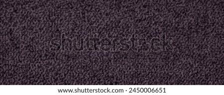 Dark purple fluffy background of soft, fleecy cloth. Texture of violet wool textile backdrop, closeup.