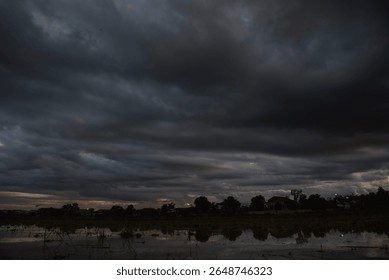 Dark rain cloud dramatic sky summer tropical thunder storm sky and fluffy black darkness cloud nearly raining cloudscape. Nimbus raincloud skyline climate background. Dark gray sky cloudy environment