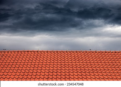 Dark Rain Clouds Above The Orange Roof. 