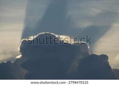 Dark rain clouds at dusk with a subtle iridescent cloud formation along the cloud edges. The soft rainbow colors are created by sunlight diffraction, producing a dramatic and peaceful atmospheric scene above towering storm clouds.