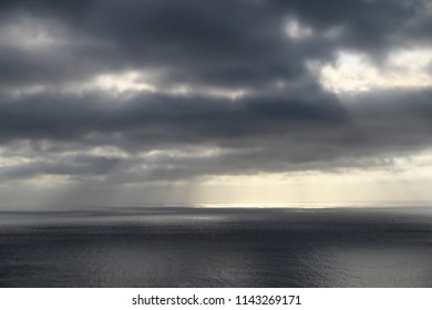 Dark rainy cloudscape at sunset with sunrays through the clouds