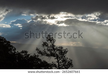 Dark rays under cloudy skys seem to radiate straight toward the viewer as the sun sets 