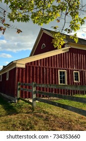 Dark Red Barn With Fence And Tree