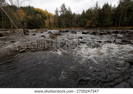 Dark river currents moving past a rocky shoreline in the parc des chutes dorwin