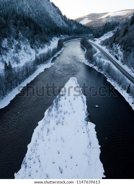 Dark river\
divided by a small island in the\
winter.