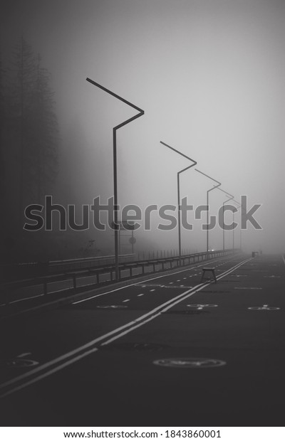 Dark road with double lines disappears into very\
thick fog