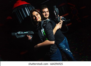 Dark room girl and funny guy playing laser tag