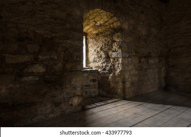 Dark room with stone walls window and wooden staircase