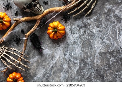 Dark Scary Halloween Background With Pumpkins, Skeleton Arms, Skull, Tree Branch With Web, Spiders, Rat On Stone Table. Flat Lay, Top View, Overhead.