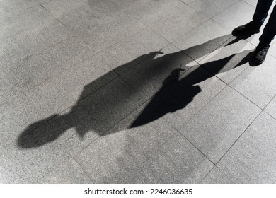 Dark shadow of a lonely person on the ground in the street. Stranger with a cigarette. Anxiety, depression, loneliness, fear concept.