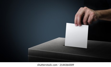 Dunkle Wahlurne mit Hand, die auf einem leeren Stimmzettel auf dunklem Hintergrund abstimmt.