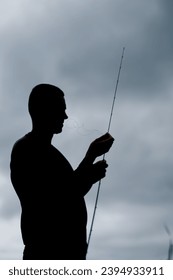 dark silhouette of a fisherman with a fishing rod on pond sport or amateur fishing - Shutterstock ID 2394933911