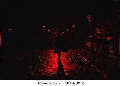dark silhouette of a male detective in a coat and hat in the rain on a night street in the style of Noir