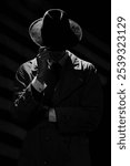 A dark silhouette of a man in a coat and hat in the noir style. A dramatic portrait in the style of detective films of the 1950s and 60s. The silhouette of a spy.