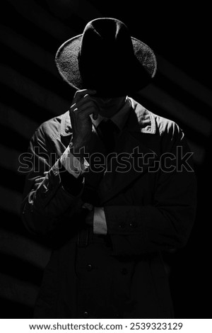 A dark silhouette of a man in a coat and hat in the noir style. A dramatic portrait in the style of detective films of the 1950s and 60s. The silhouette of a spy.