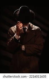 A Dark Silhouette Of A Man From The Face In A Coat And Hat. A Dramatic Portrait In The Style Of Detective Films And Spy Books Of The 1950s And 60s.