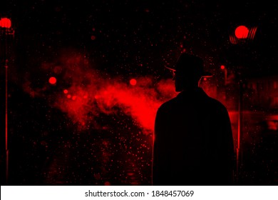 Dark Silhouette Of A Man In A Hat In The Rain On A Night Street In A City In The Style Of Noir