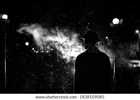 dark silhouette of a man in a hat in the rain on a night street in a city in the style of Noir